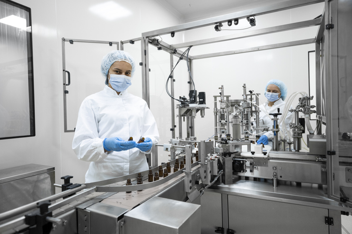 Two fully equipped coworkers in protective workwear seen in a pharmaceutical laboratory